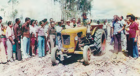 Registro fotográfico de Alysson Paolinelli sobre um trator, rodeado de trabalhadores
