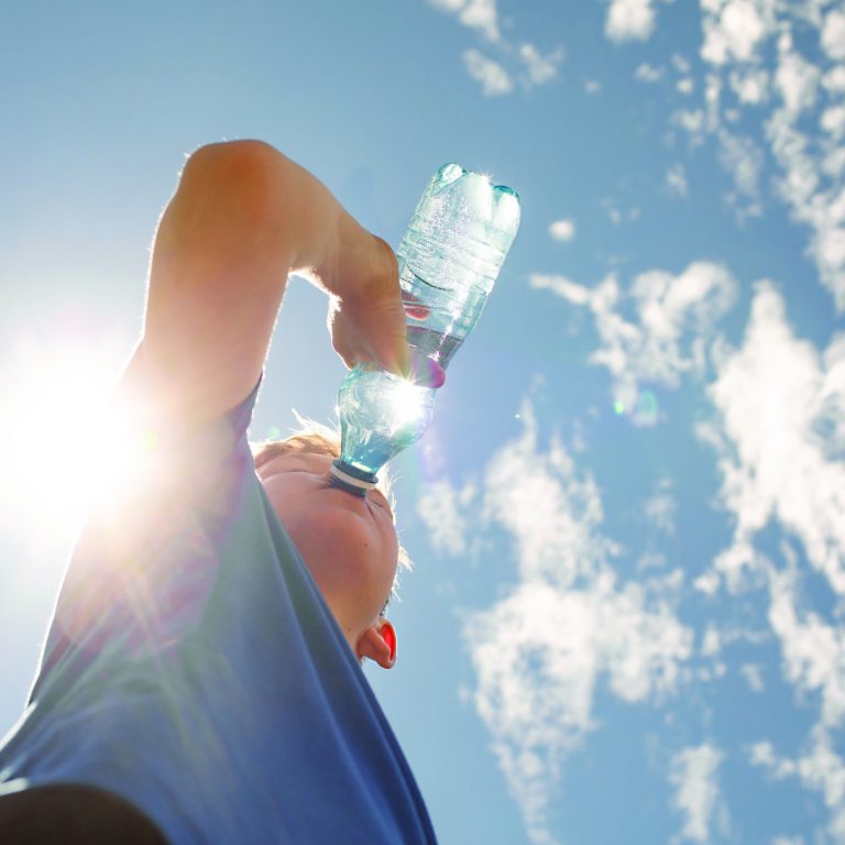 Active sporty child drinking from bottle of water outdoors