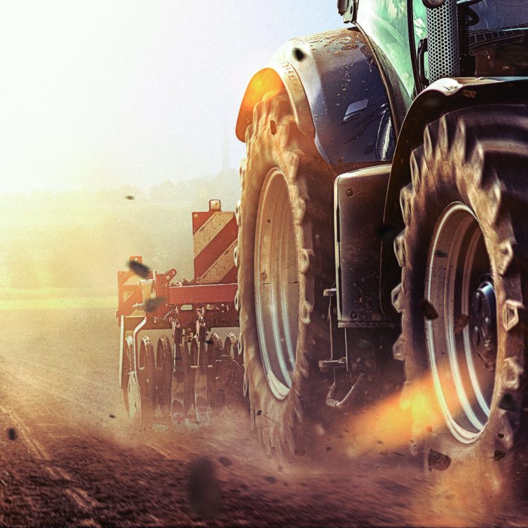 tractor in the field pulls plough or cultivator to loosen the soil and prepare it for sowing in bright sunshine