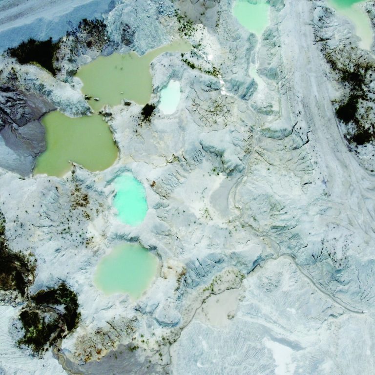 belitung, Indonesia on march 3, 2025: defocused. Aerial view of an open-pit mining site with excavators and turquoise water pools. Industrial landscape of mineral extraction area. Selective focus