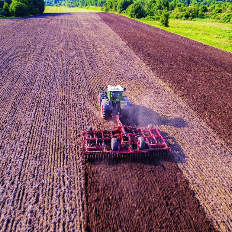 Aerial view of tractor cultivating field with harrow.  farmer prepares a field for sowing