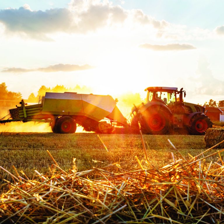 Tractor baling straw in field