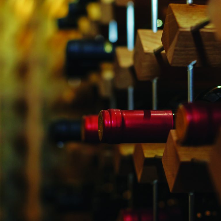 Red wine bottles arranged neatly in a wooden rack, showcasing the beauty of wine collection and storage.