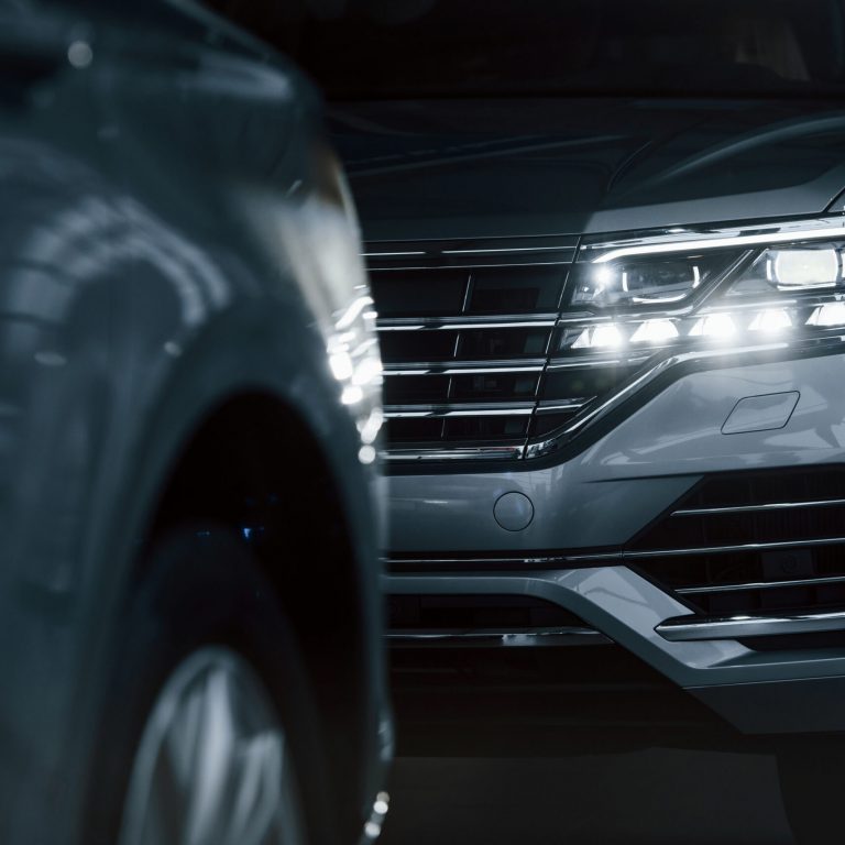 Powerful headlights. Particle view of modern luxury cars parked indoors at daytime.